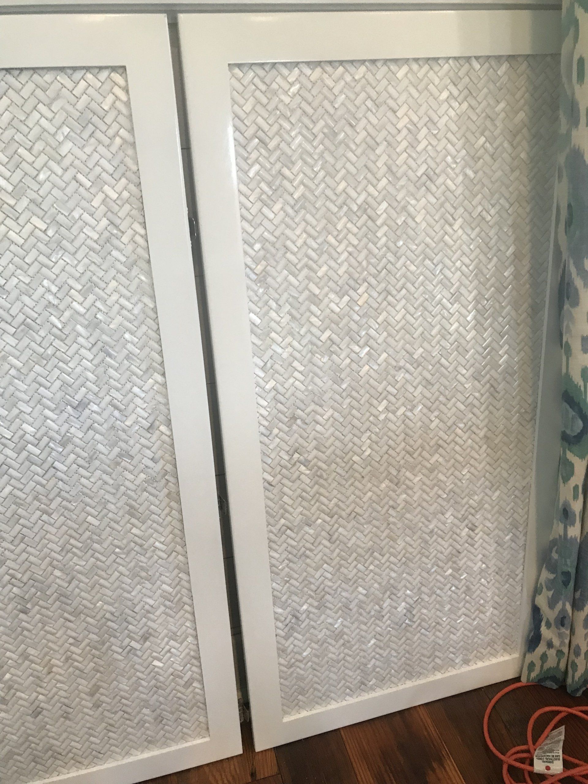 Two white cabinet doors with a herringbone pattern mosaic tile.