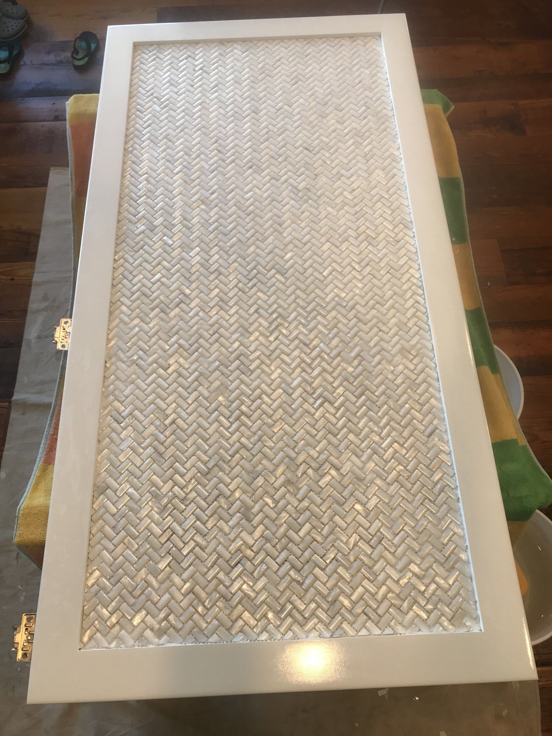White-framed cabinet door with a herringbone pattern in a light neutral color.