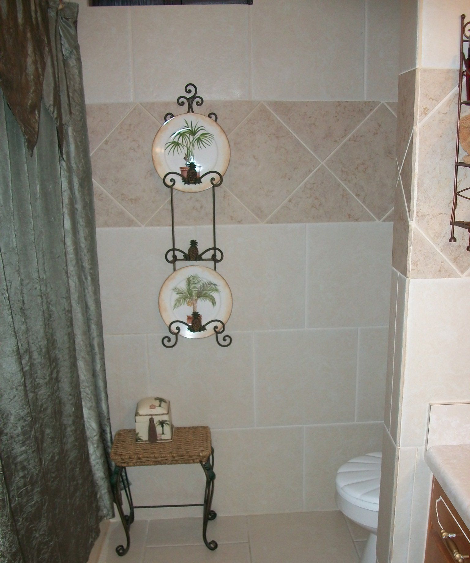 Bathroom with beige tiles, decorative plates, and a small table.