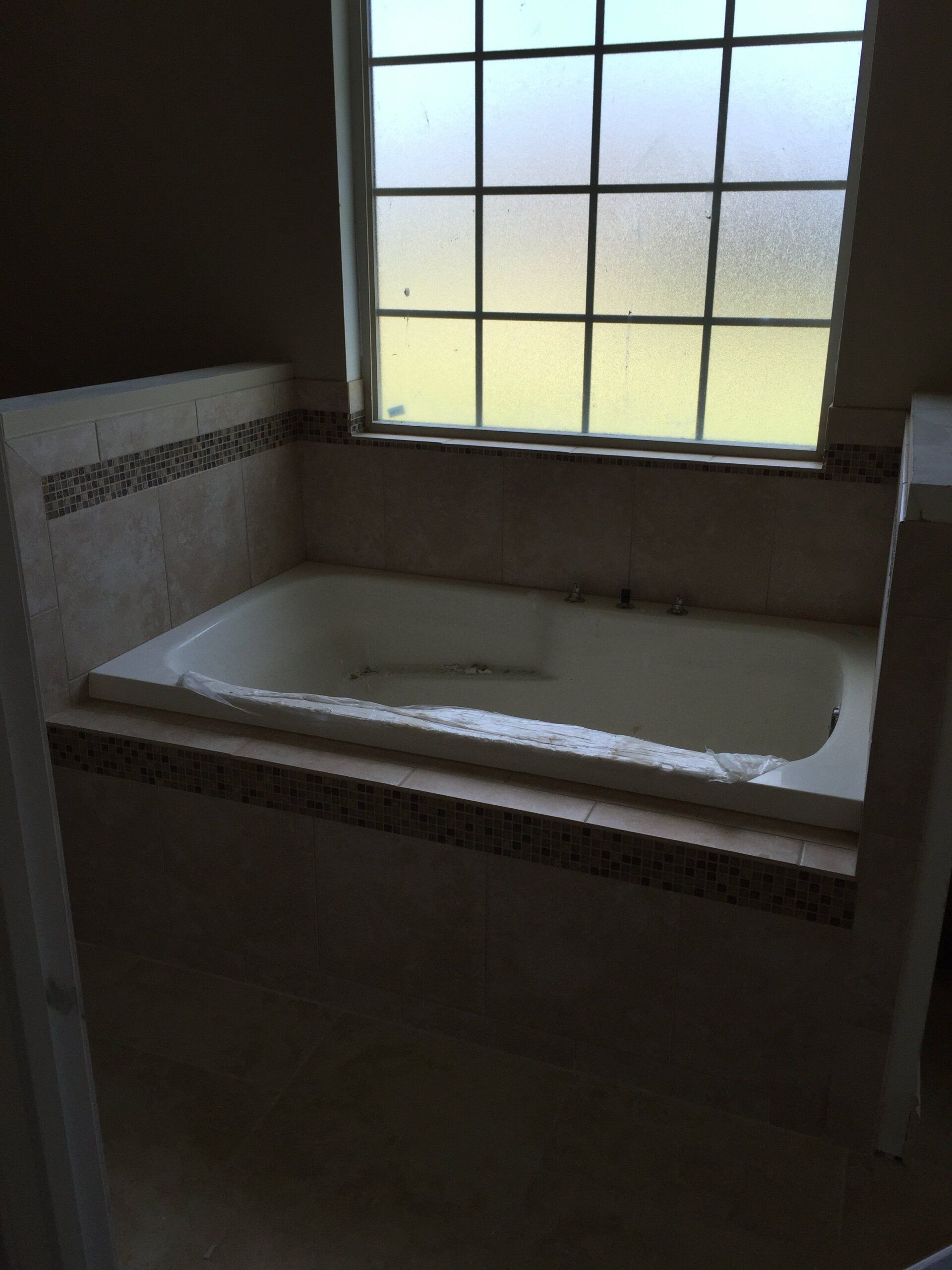 Bathroom with built-in bathtub, tile surround, and frosted window.