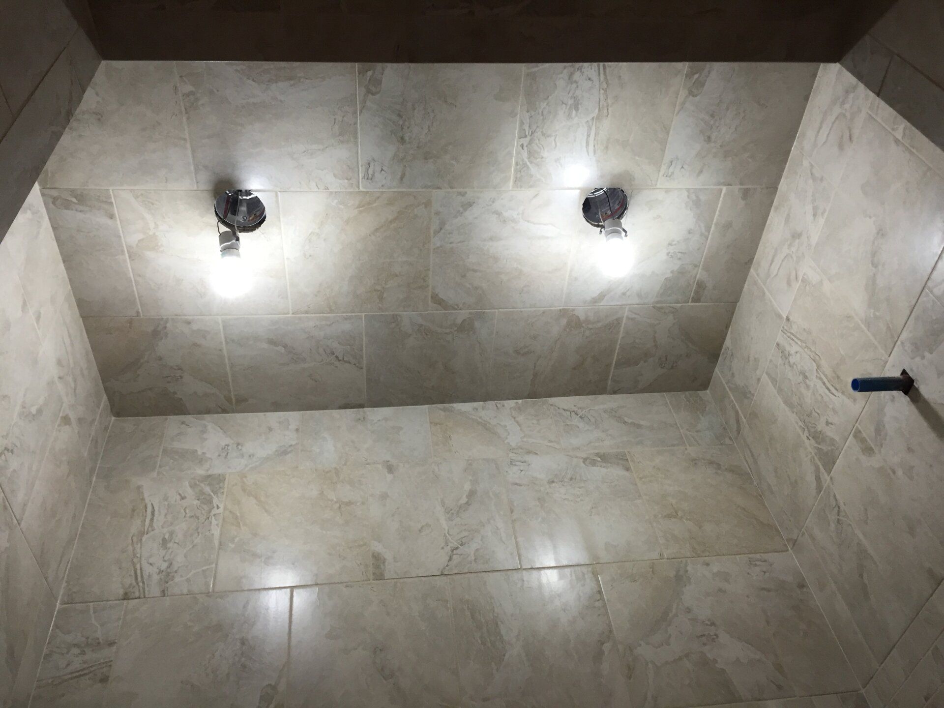 Tiled shower ceiling with two lights.