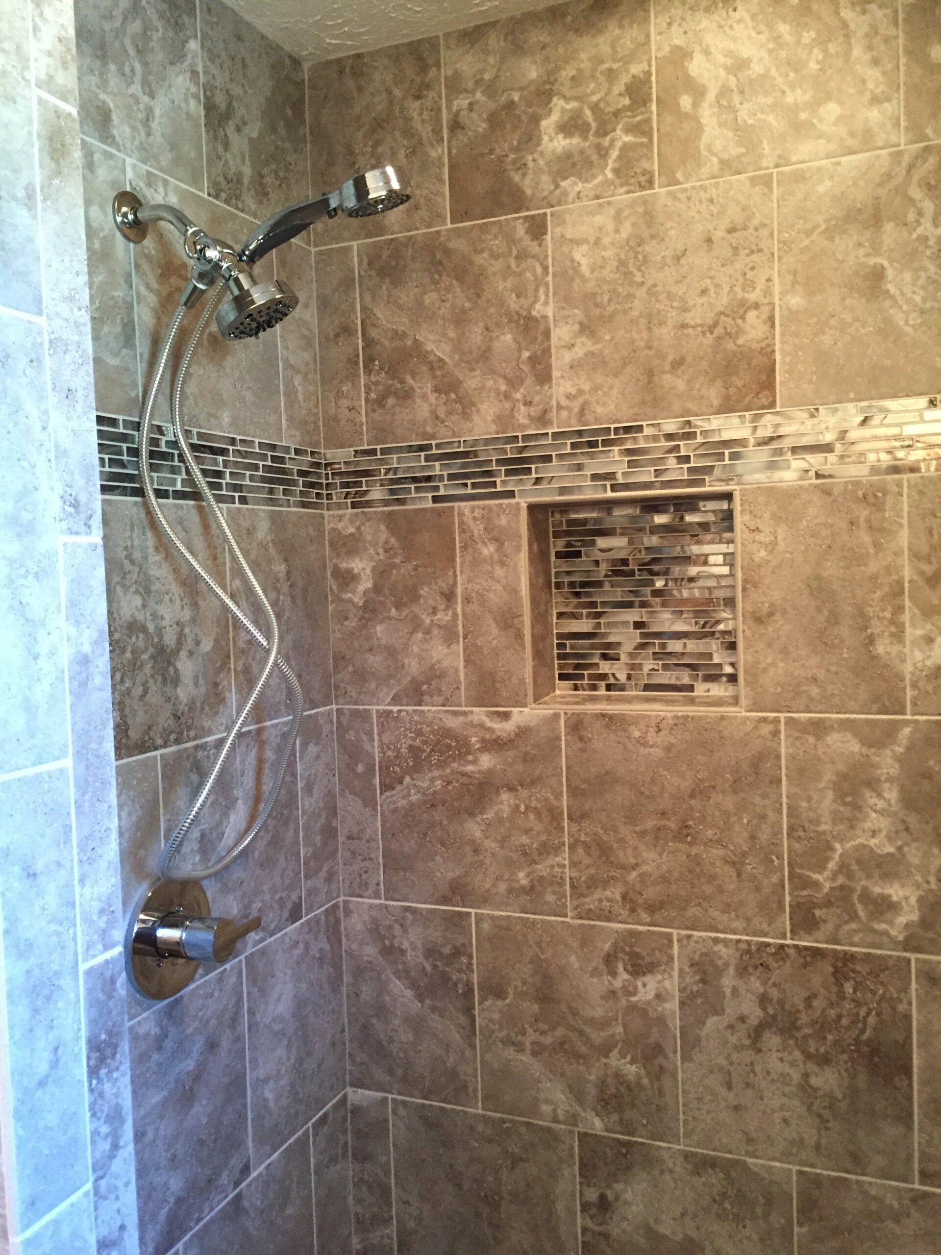 Shower with brown tile walls, decorative tile stripe, and showerhead.