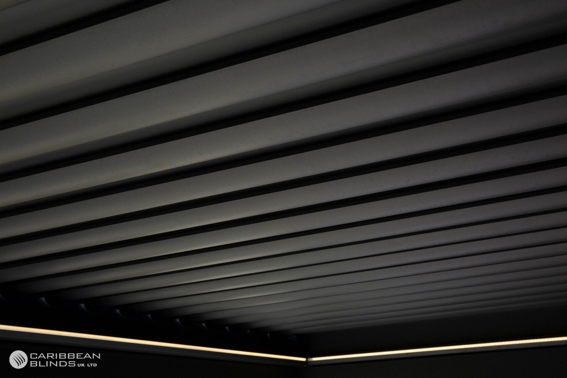A low-angle view of a modern black louvered ceiling with integrated perimeter lighting.