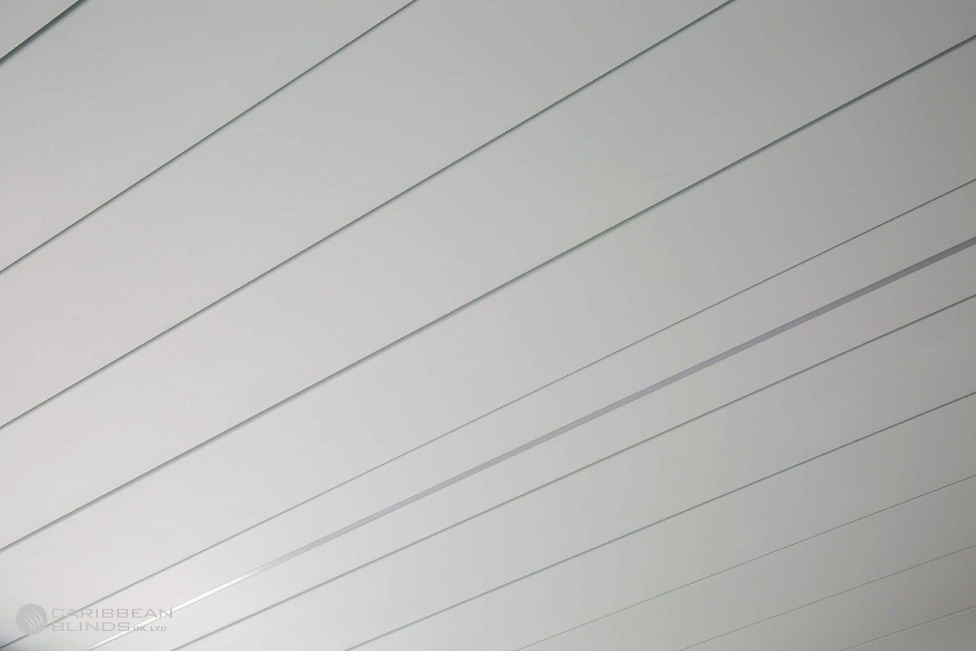 A white, slatted ceiling showing a series of parallel lines and joints spanning across the frame.