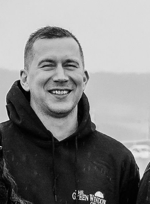 A smiling person wearing a black hooded sweatshirt with