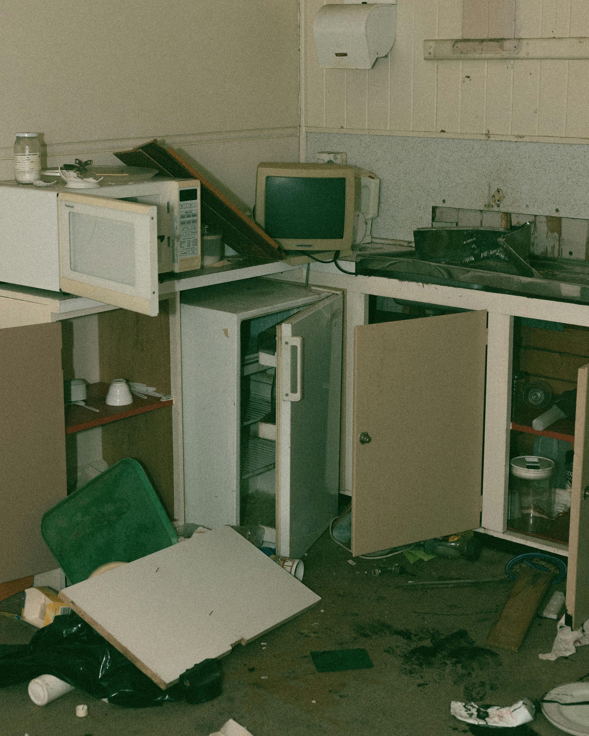 Messy kitchen with an open fridge, microwave, and scattered debris.