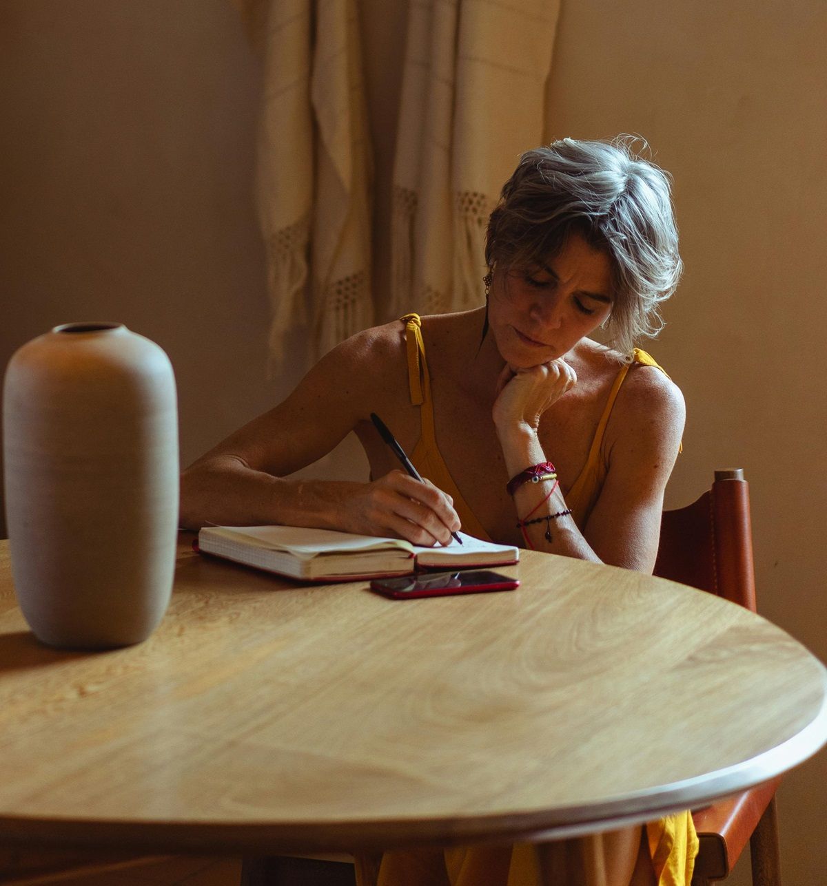 older-woman-with-short-hair-writing-at-small-dining-table