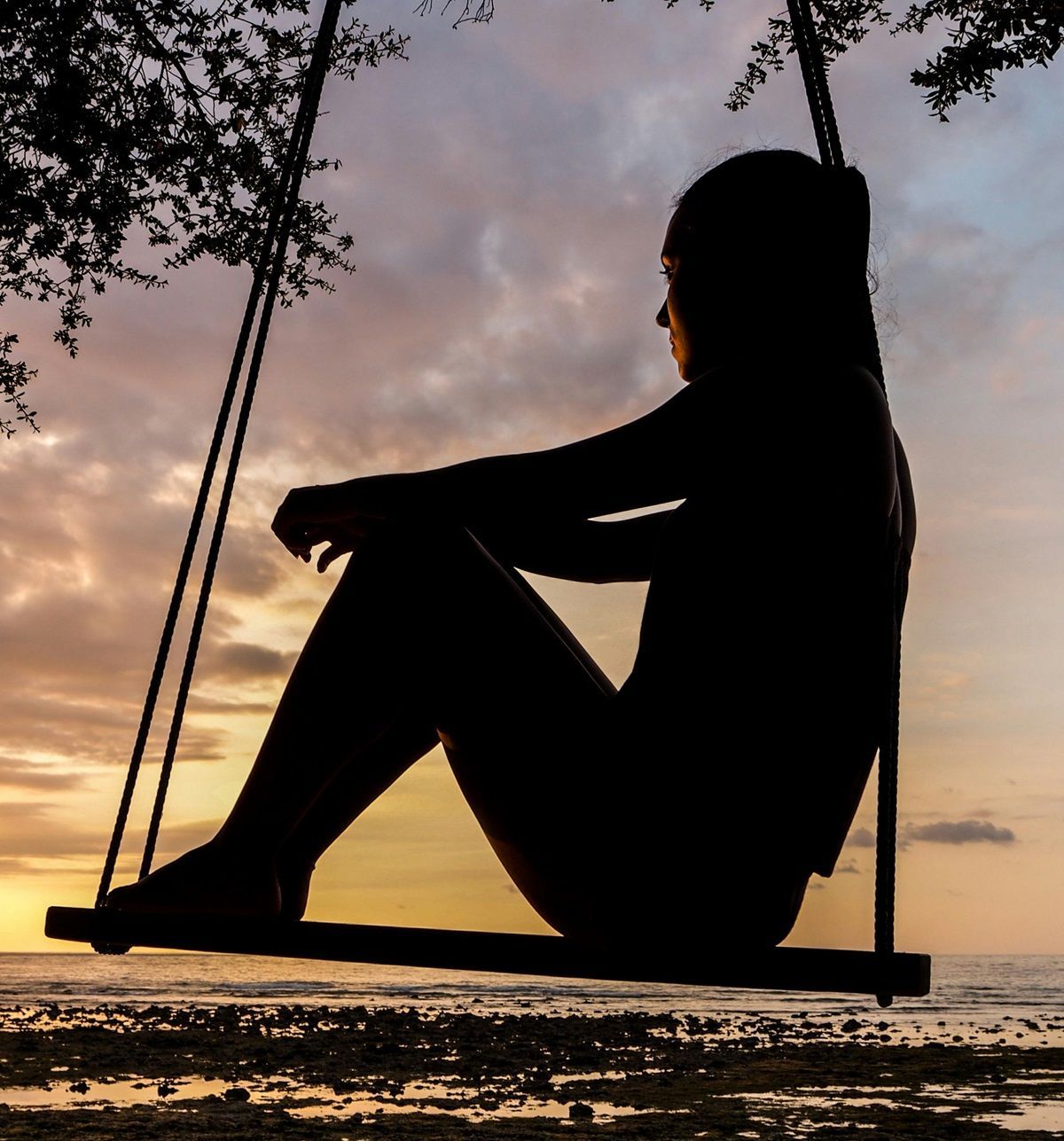 Person-silhouette-at-sunset-sitting-on-swing-sad-and-pondering