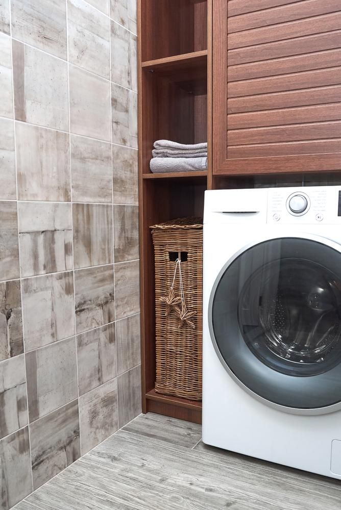 A Washing Machine Is Sitting in A Laundry Room Next to A Wicker Basket — Bowral Bathrooms in Exeter, NSW