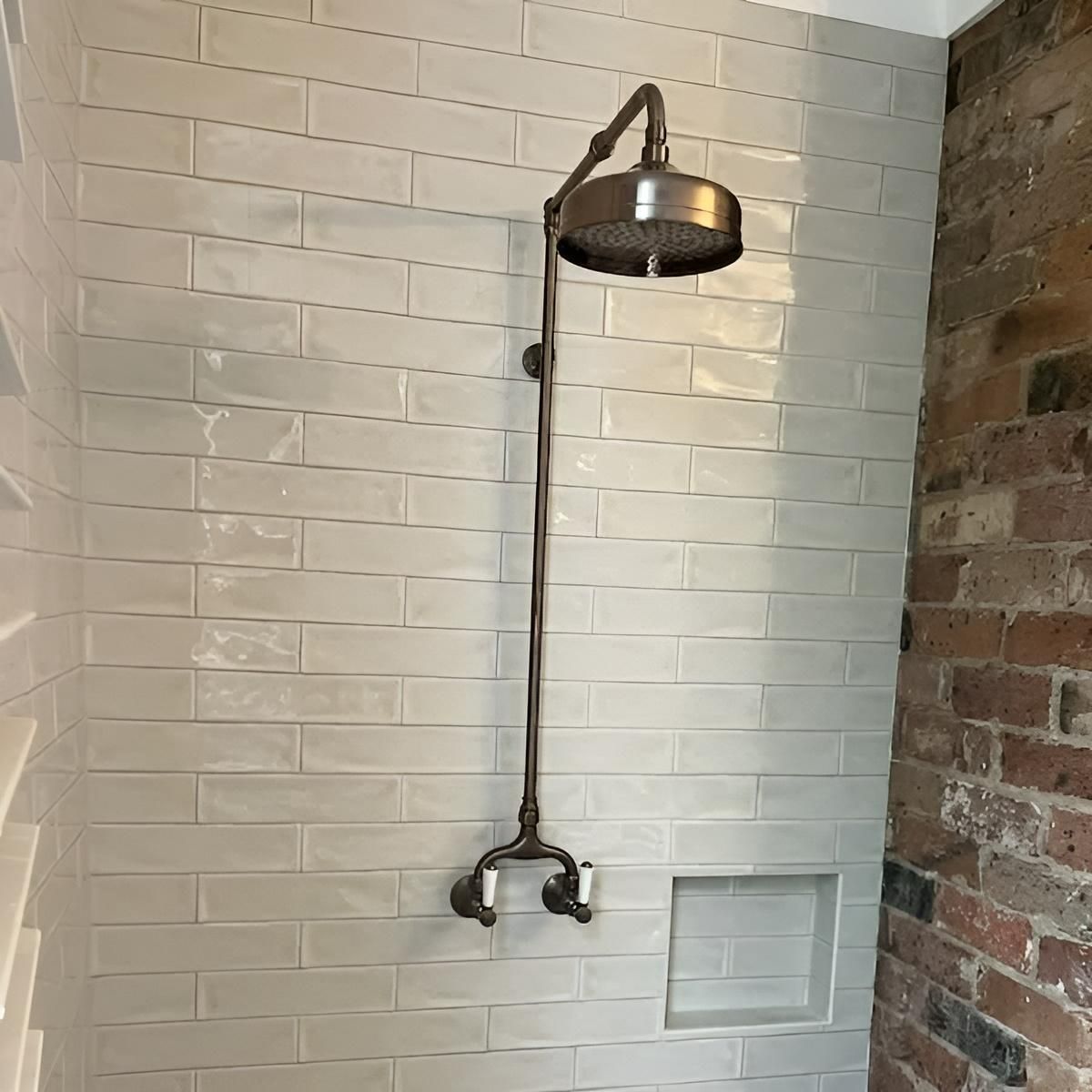 A Shower Head Is Hanging from A Brick Wall in A Bathroom — Bowral Bathrooms in Bundanoon, NSW