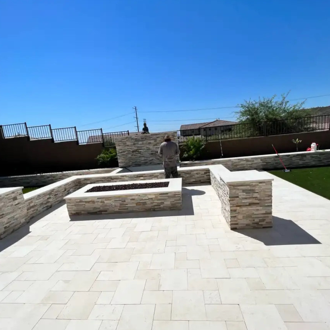 A man is standing in front of a fire pit on a patio.