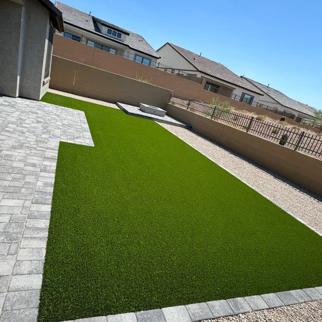 A large lawn with a brick walkway and a house in the background.
