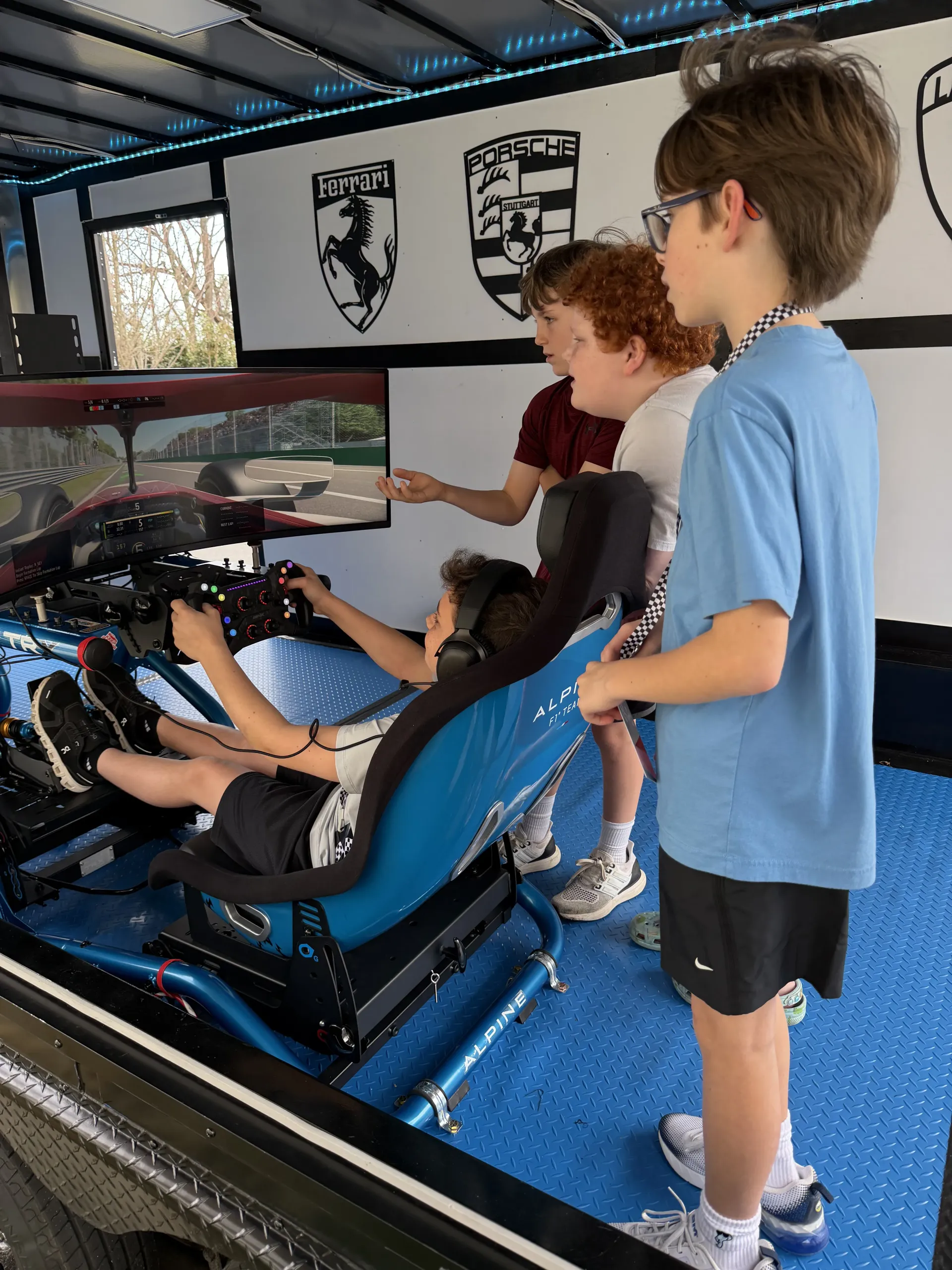 Children driving a racing simulator in a mobile racing simulator experience trailer.