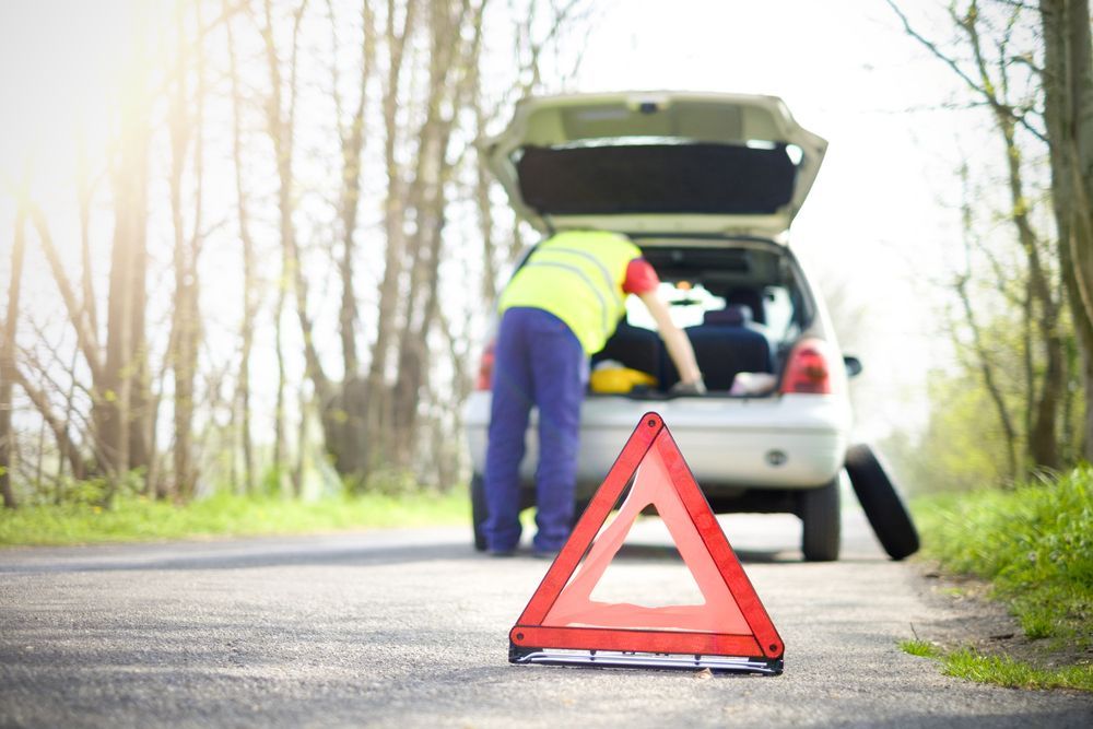 Man is Changing a Tire on a Broken Down Car — 365 Towing Taree in Forster, NSW
