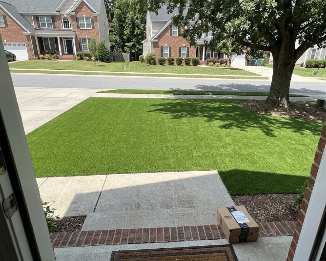 A beautiful modern house in Raleigh NC with a perfectly green artificial turf front lawn.