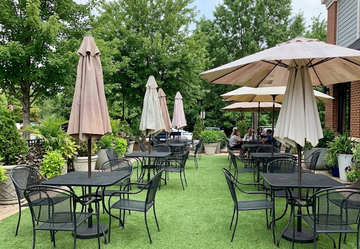 Outdoor restaurant patio featuring clean and durable synthetic grass installation under dining tables.