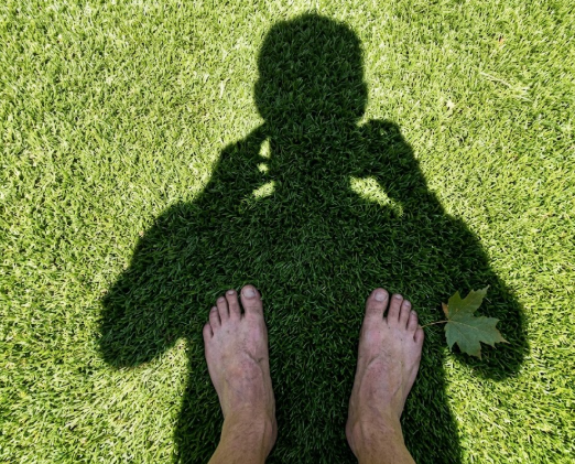 Close up view of bare feet standing on soft residential artificial grass.