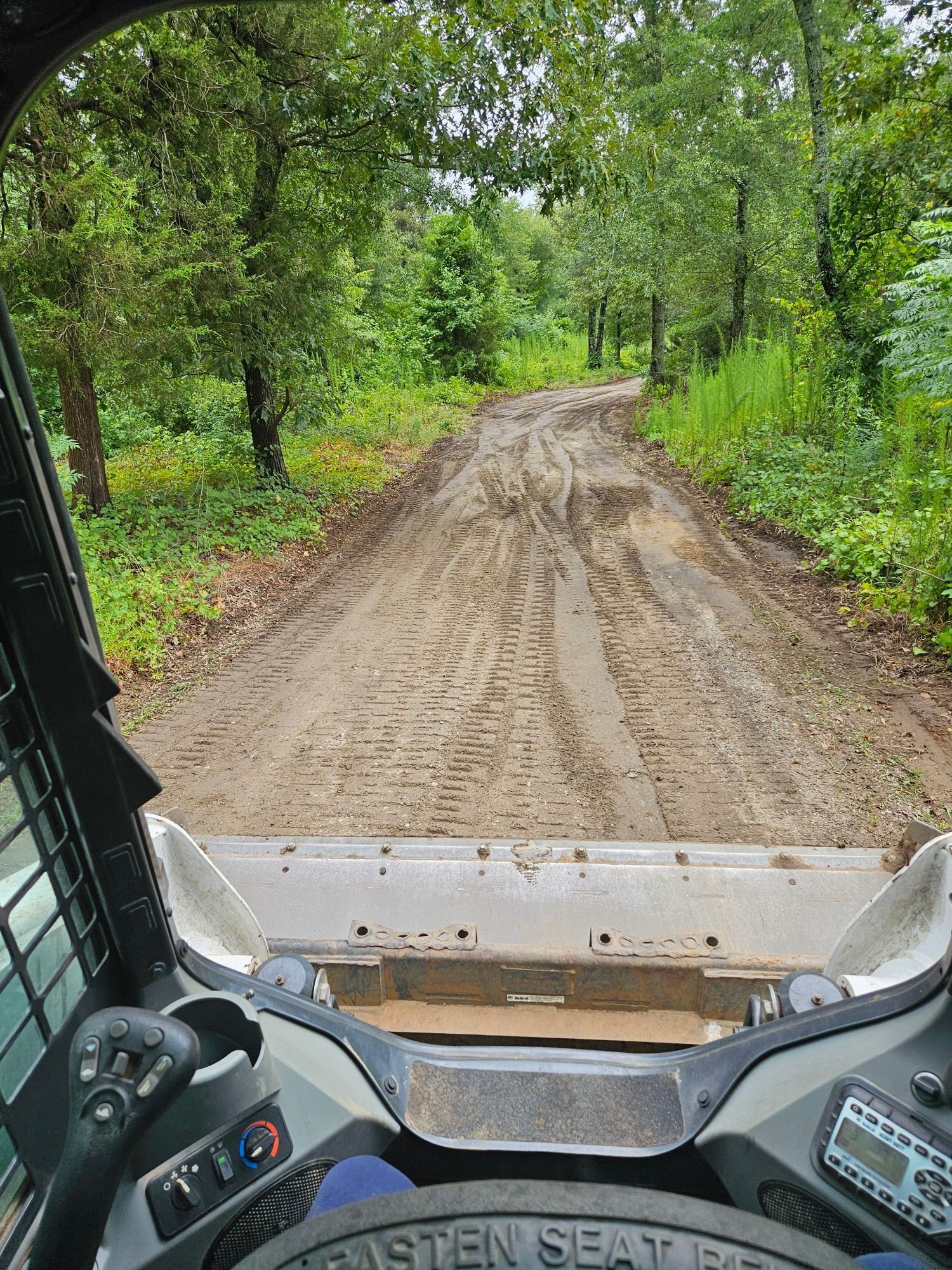 A person is driving a bulldozer down a dirt road.