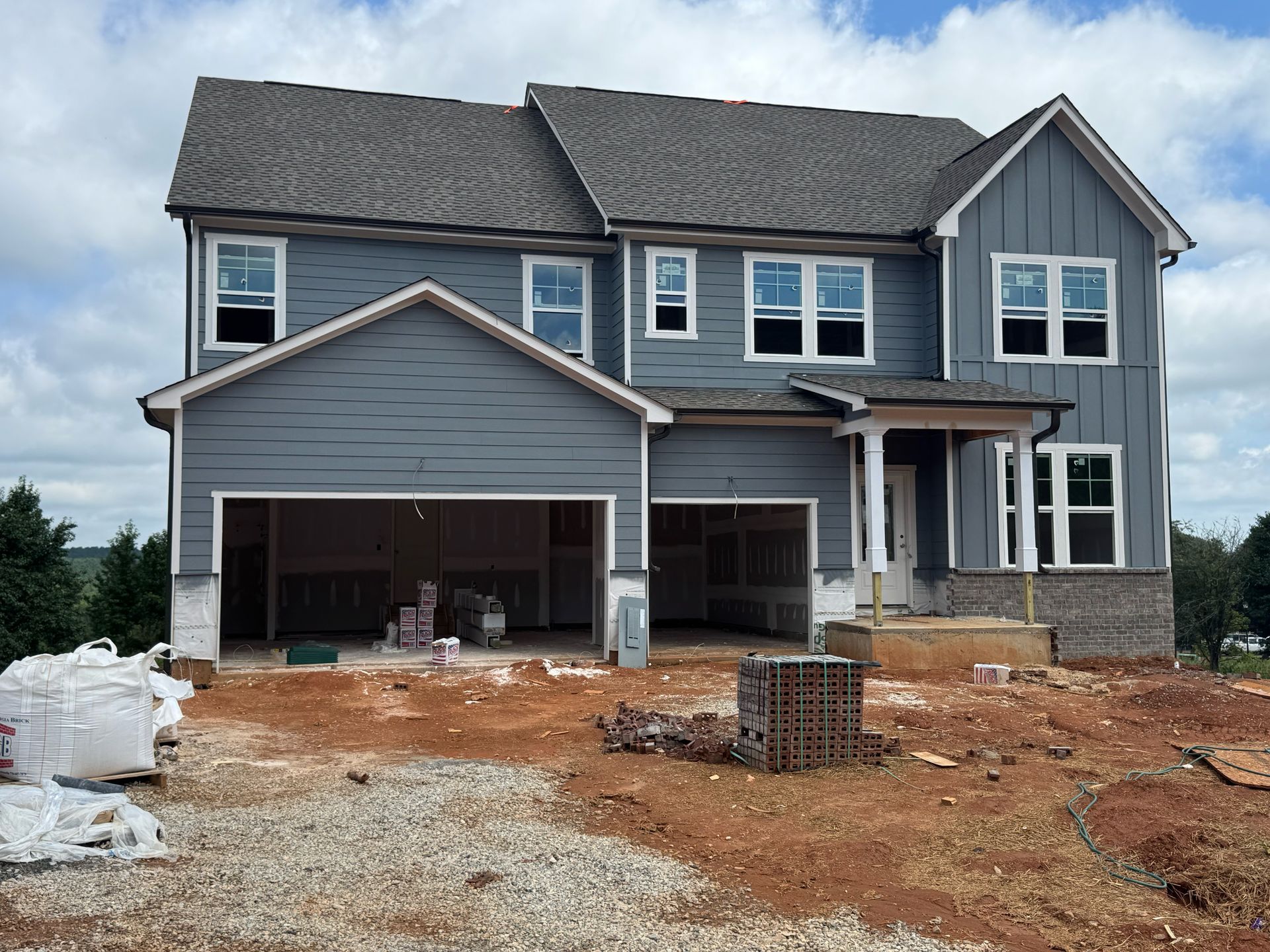 A large house is being built on a dirt hill