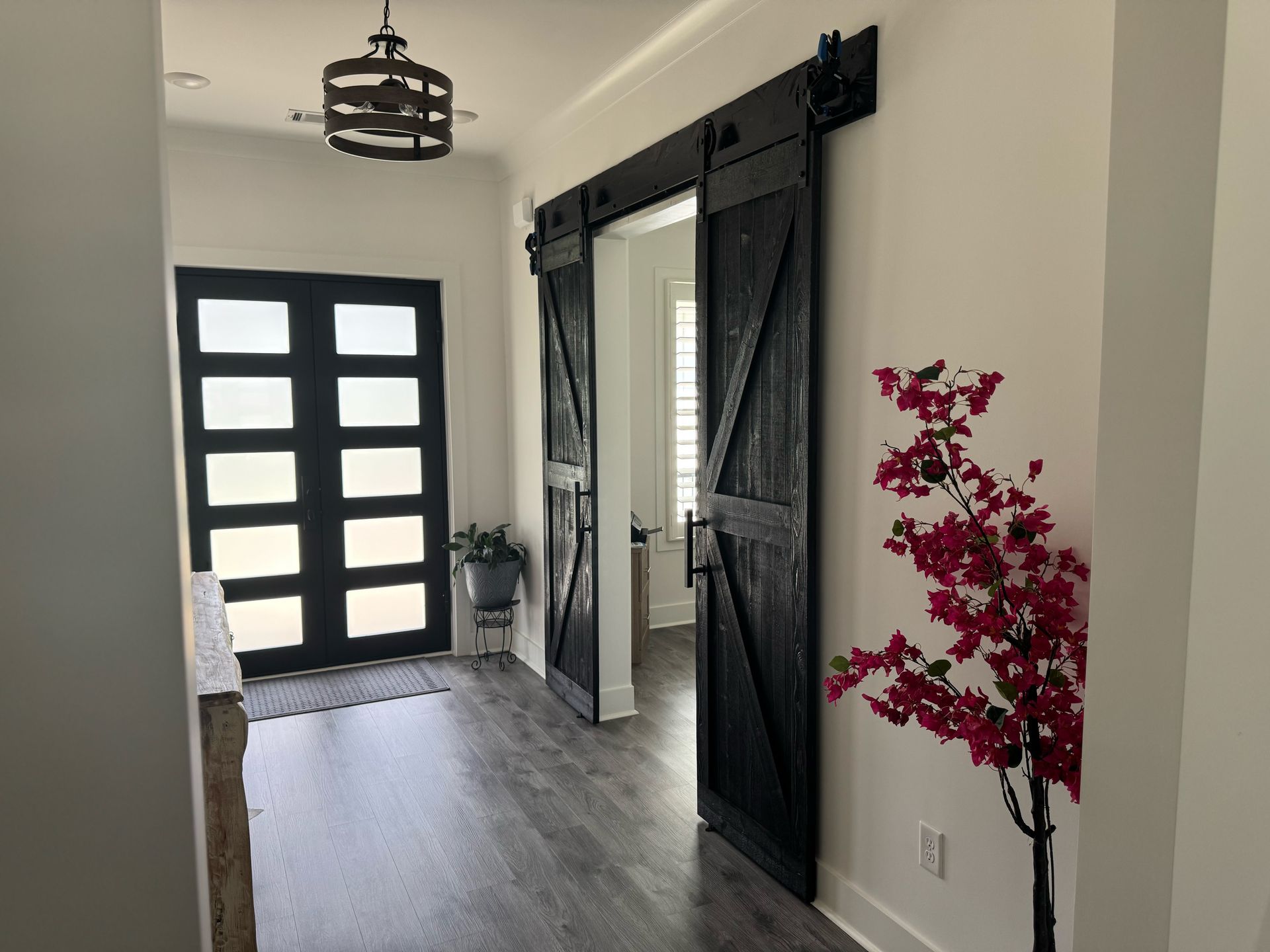 A hallway with sliding barn doors and a tree in the corner.