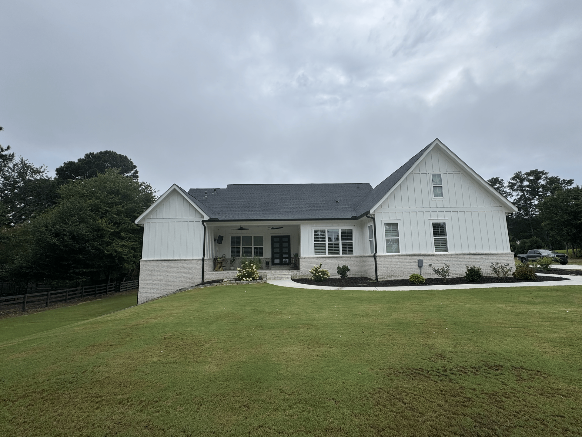 A white house with a blue roof is sitting on top of a lush green field.