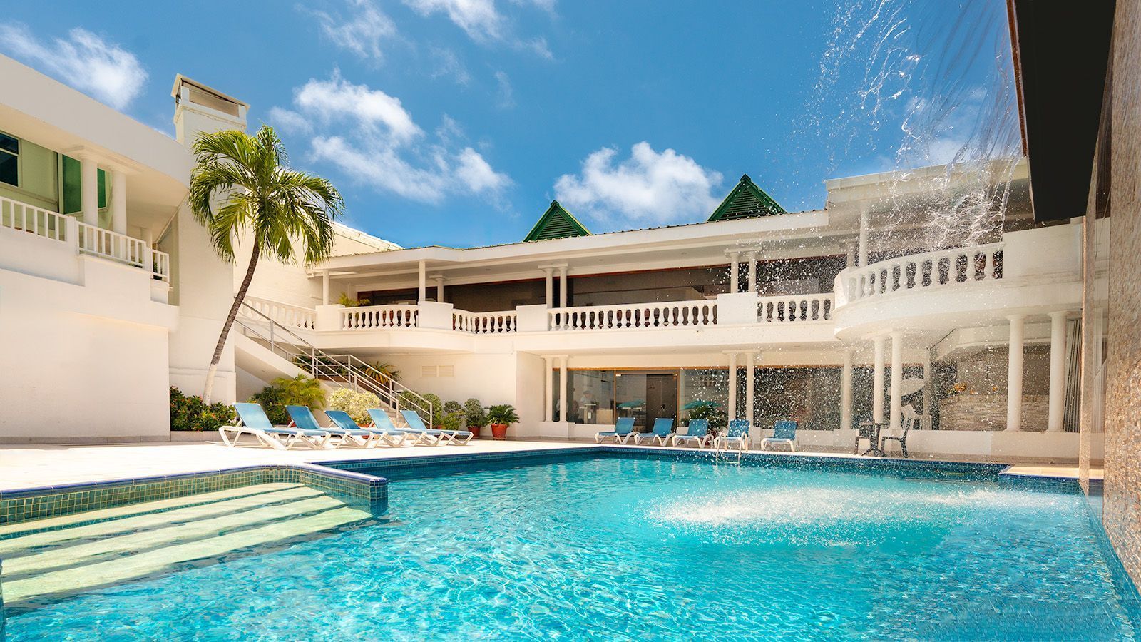 Hotel in San Andrés with outdoor pool, surrounded by rooms and tropical palm trees.