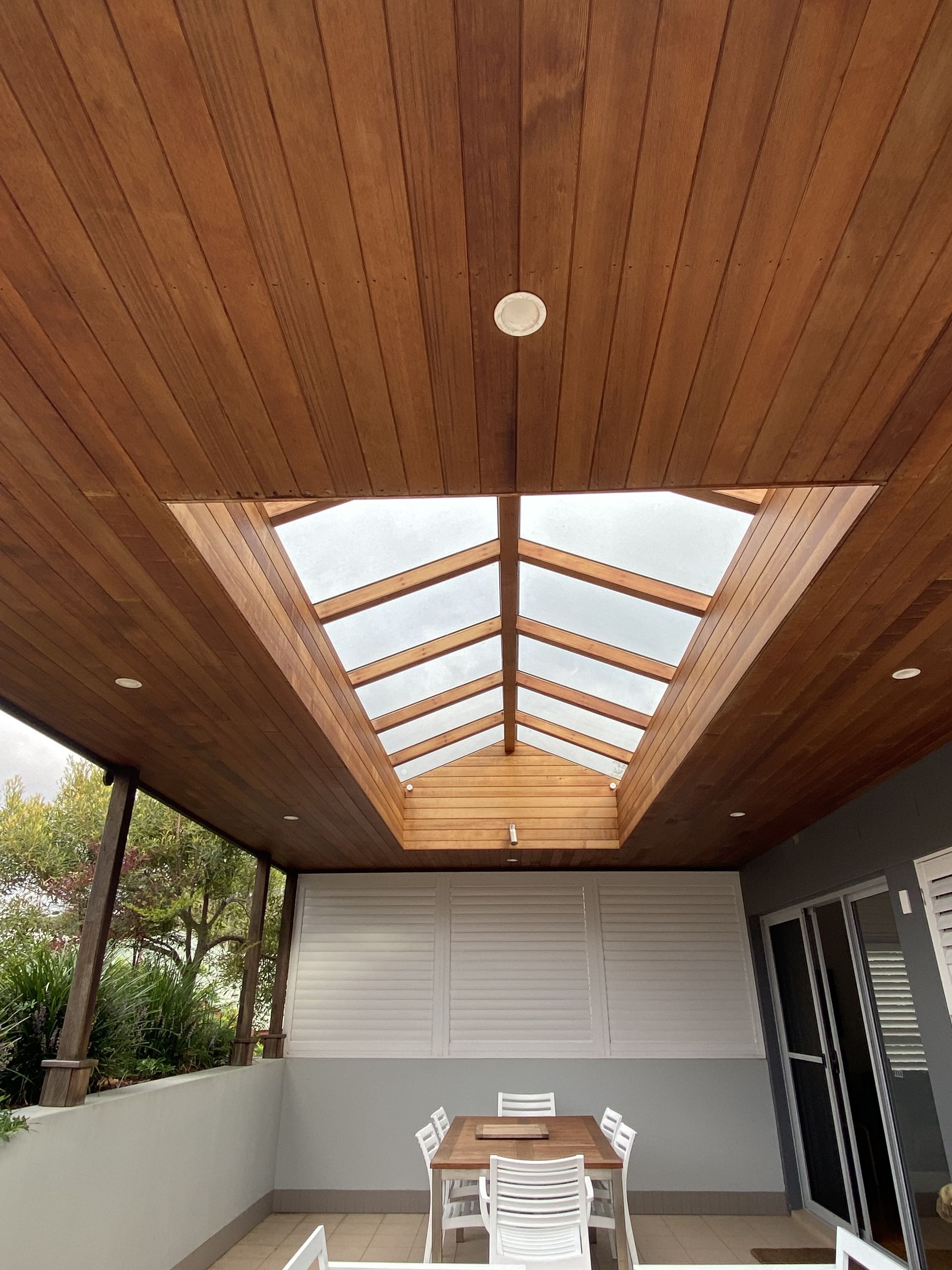 Wooden ceiling with a skylight and a patio dining set. — CAW Services in Badagarang, NSW