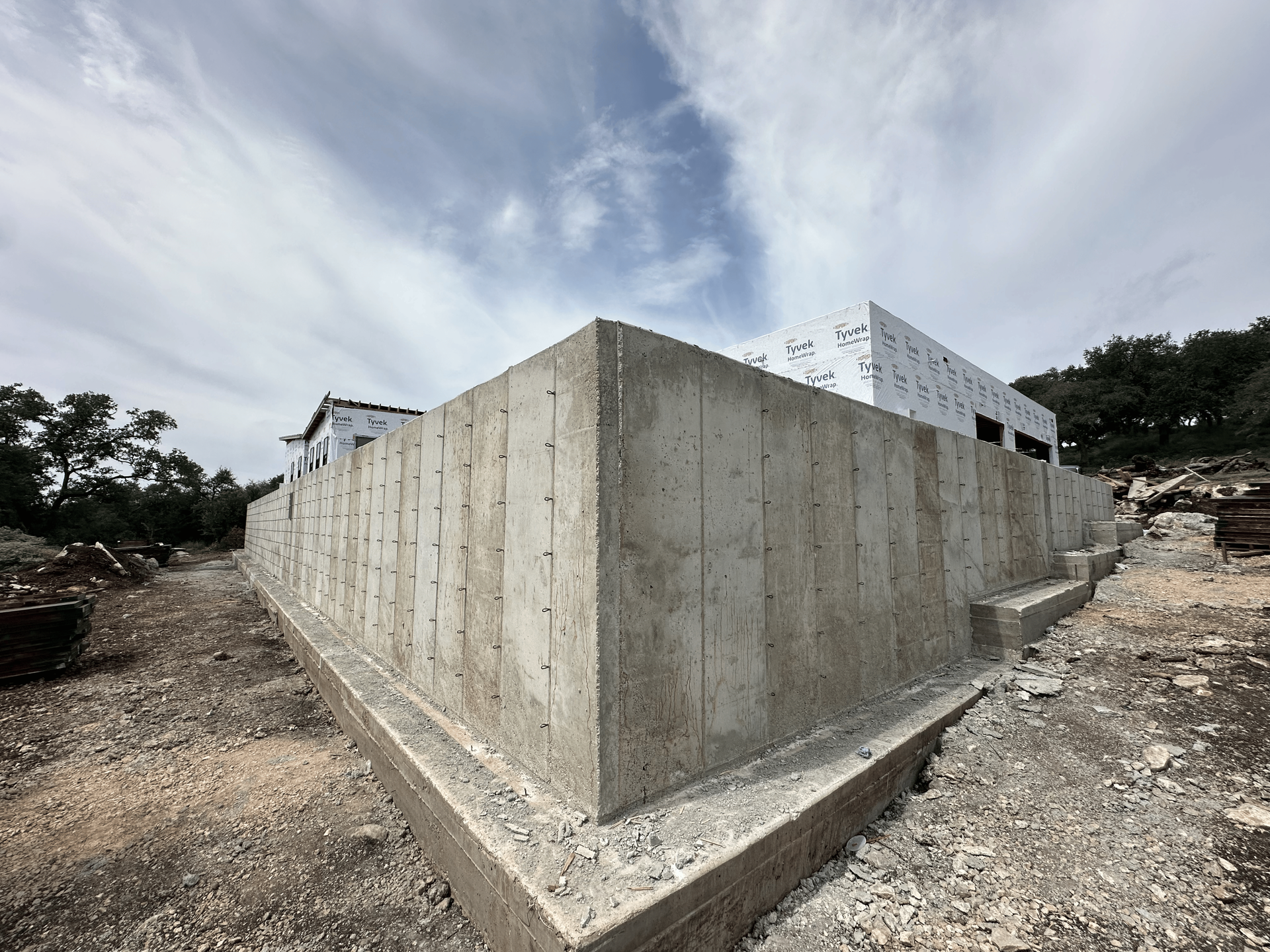 Concrete foundation corner of a building under construction, exterior view, cloudy sky.