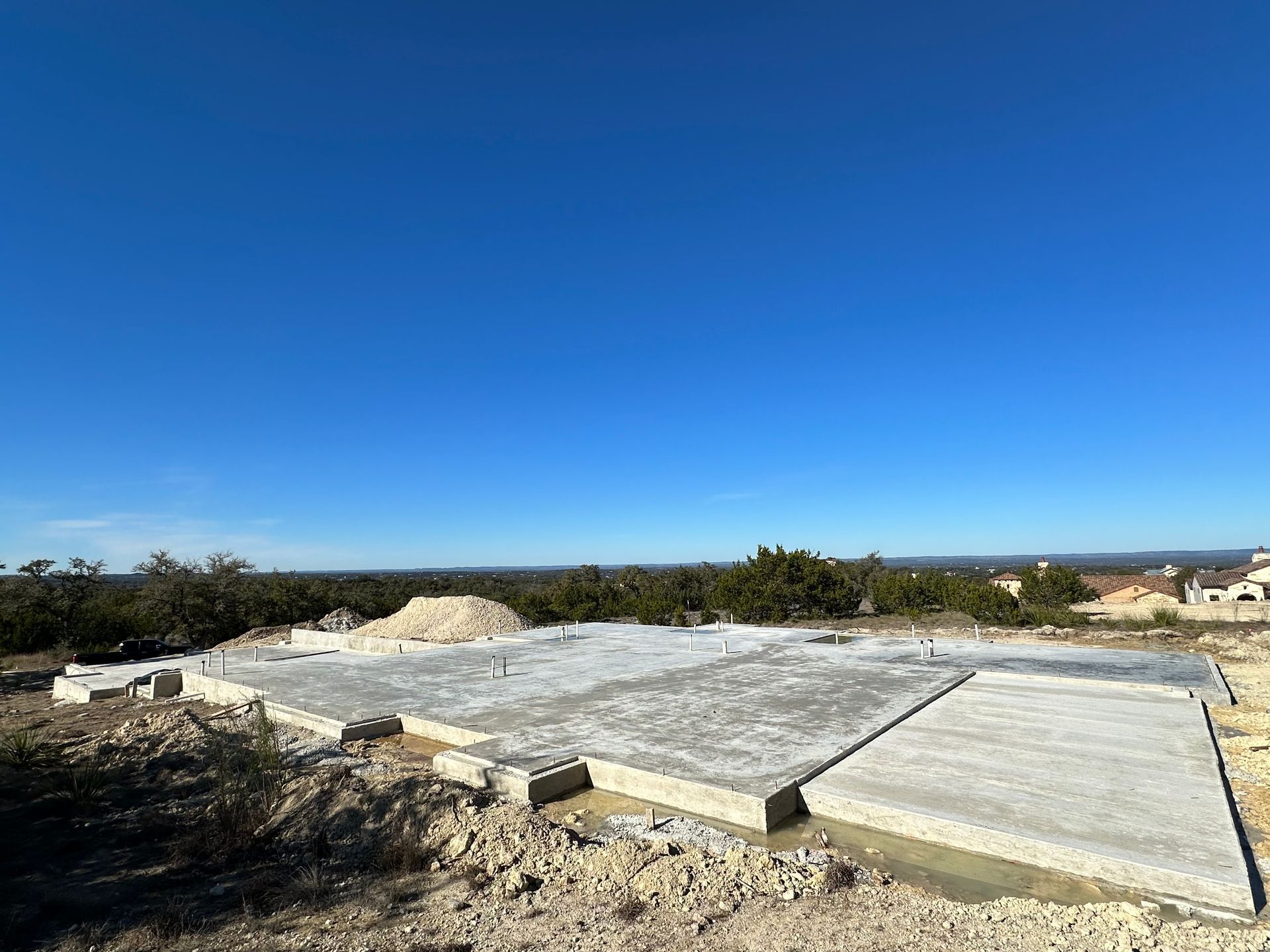 A large concrete base for a house is being built on top of a hill.
