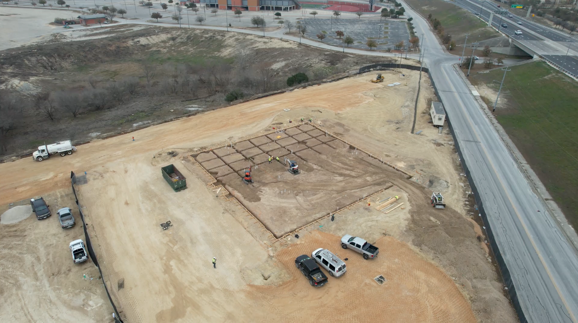 An aerial view of a construction site next to a highway.