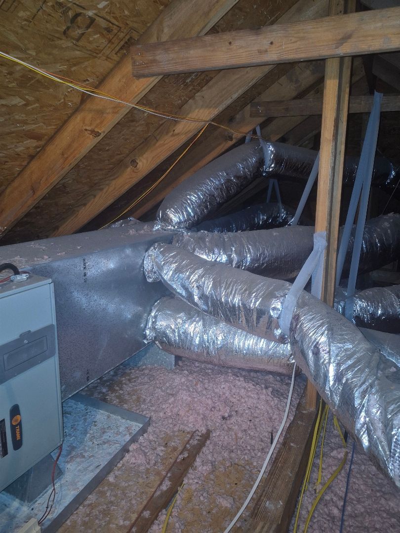 Attic with insulated ductwork, exposed wooden beams, and HVAC equipment on the left.
