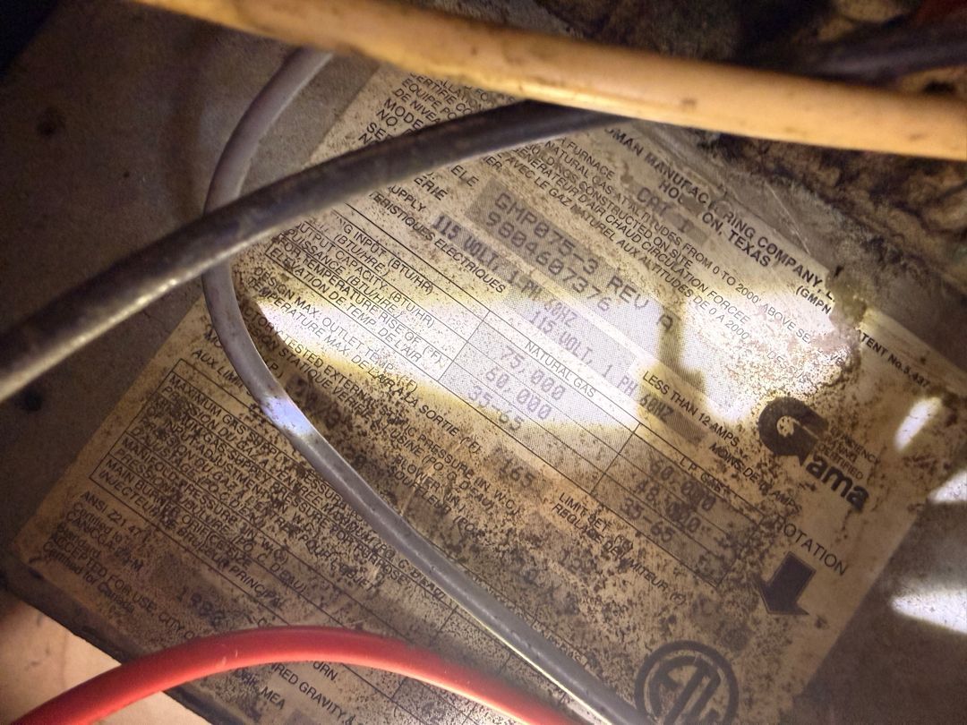 Close-up of tangled red, black, and tan wires over a worn electrical label inside a device.
