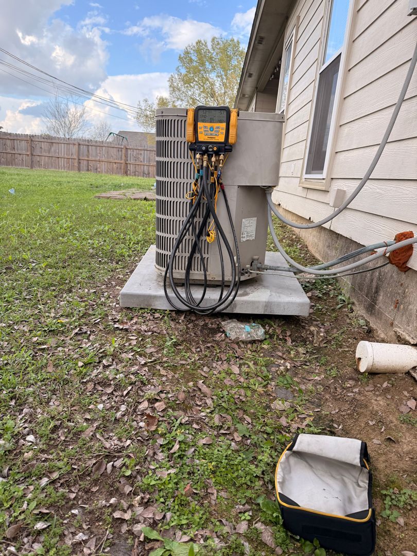 Outdoor HVAC unit beside a house, with exposed wiring and a small toolbox on the ground.
