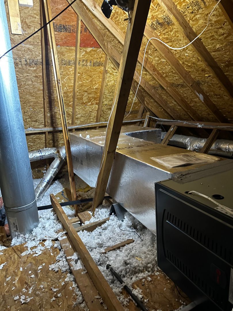 Attic with exposed wooden rafters, insulation, ductwork, and a furnace unit on the right.