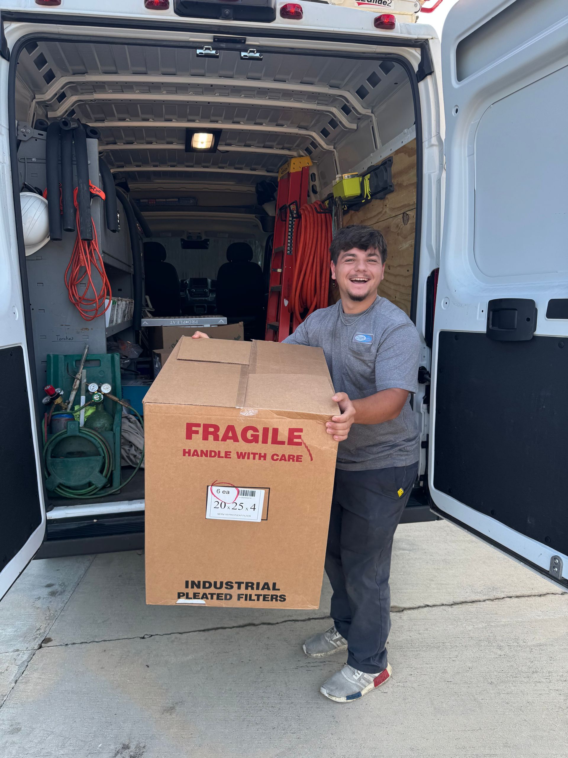 Person smiling while holding a large fragile box in the back of a moving van.