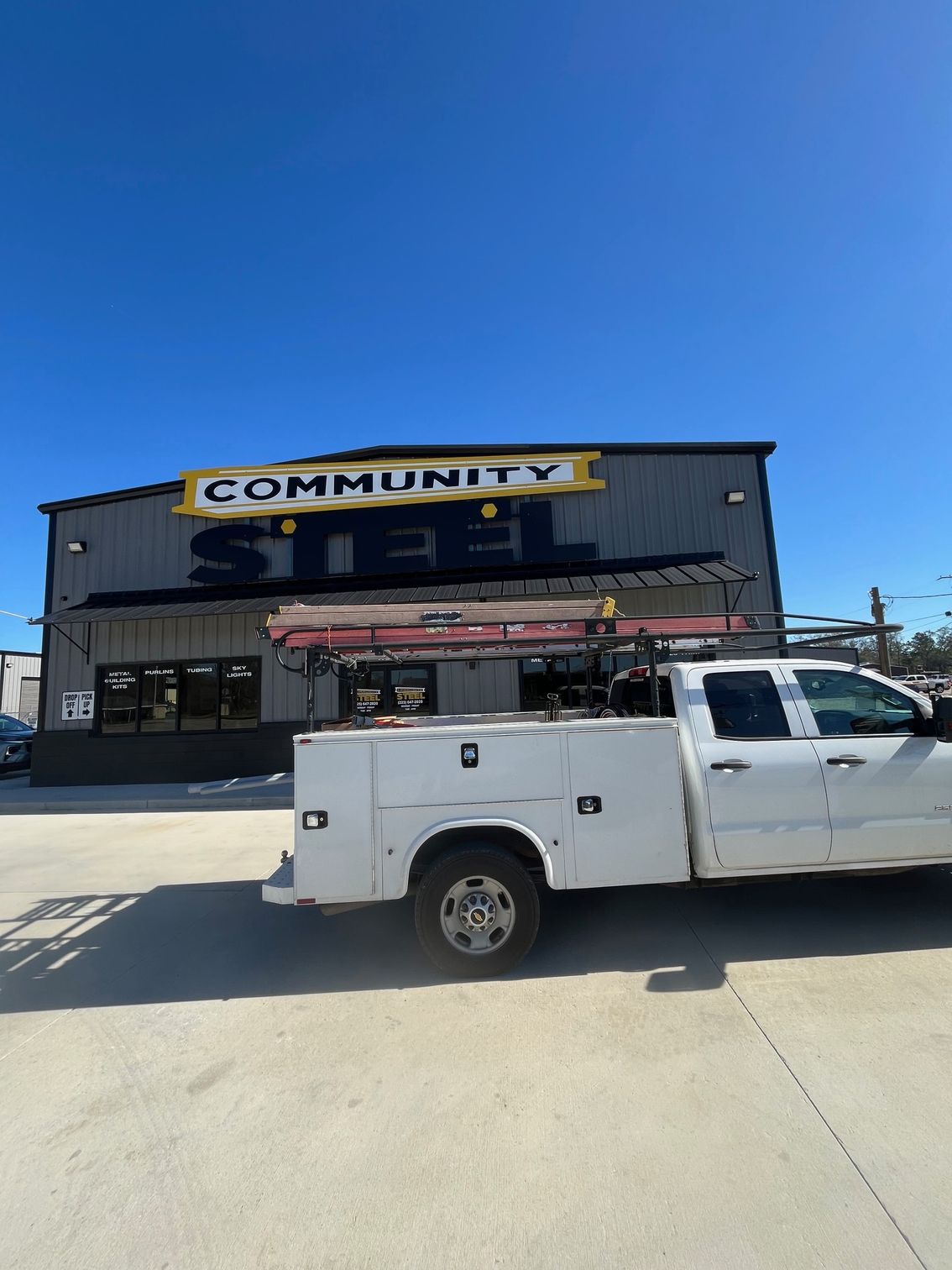 White utility truck parked outside a Community store under a clear blue sky