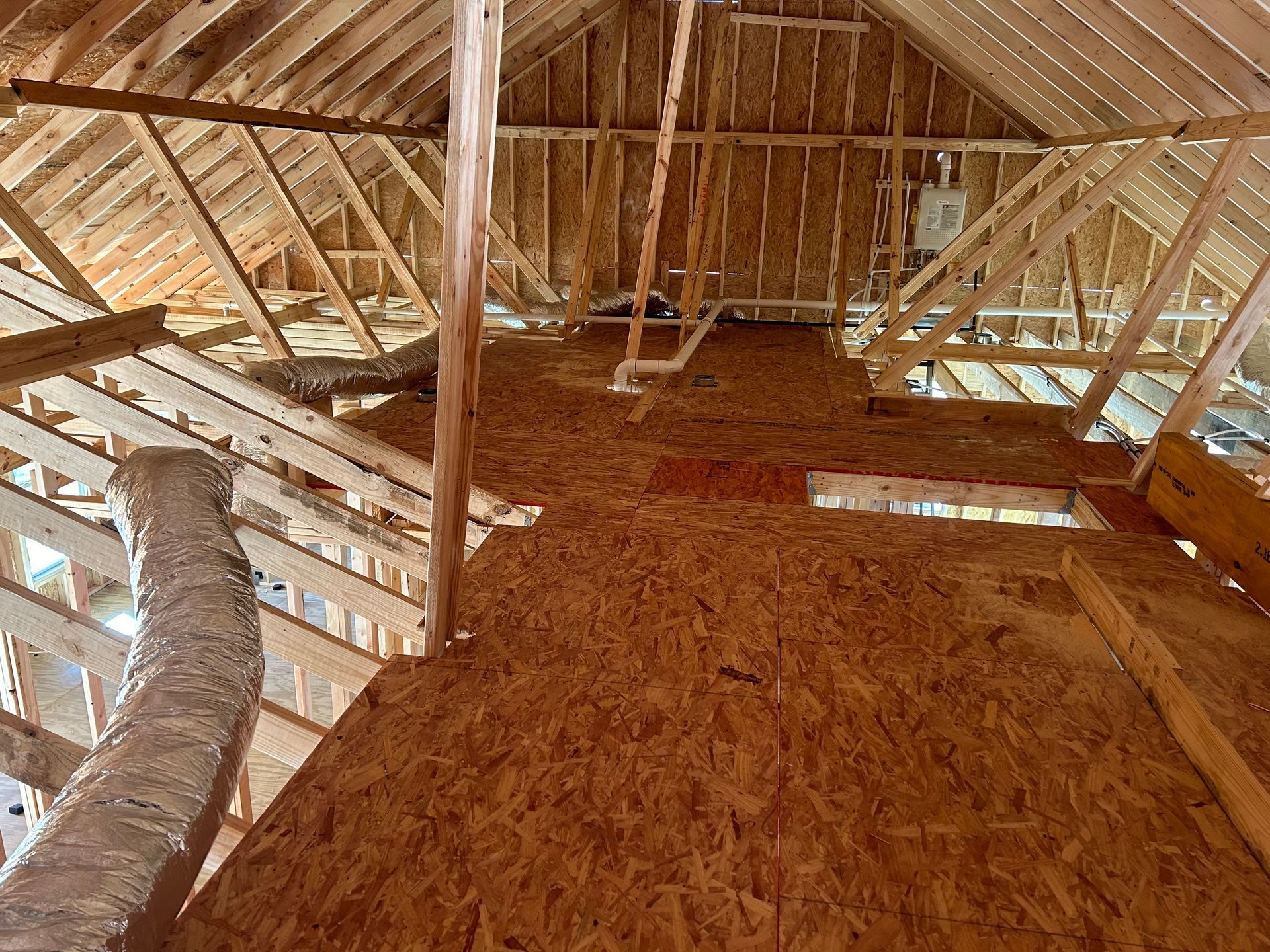 Attic loft with exposed wooden beams and a sloped wood-plank floor under construction