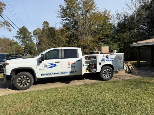 White utility truck with work tools parked on grass beside a house in a suburban yard.
