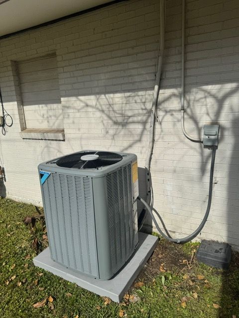 Outdoor air conditioner unit beside a house wall with electrical conduit and window shutters