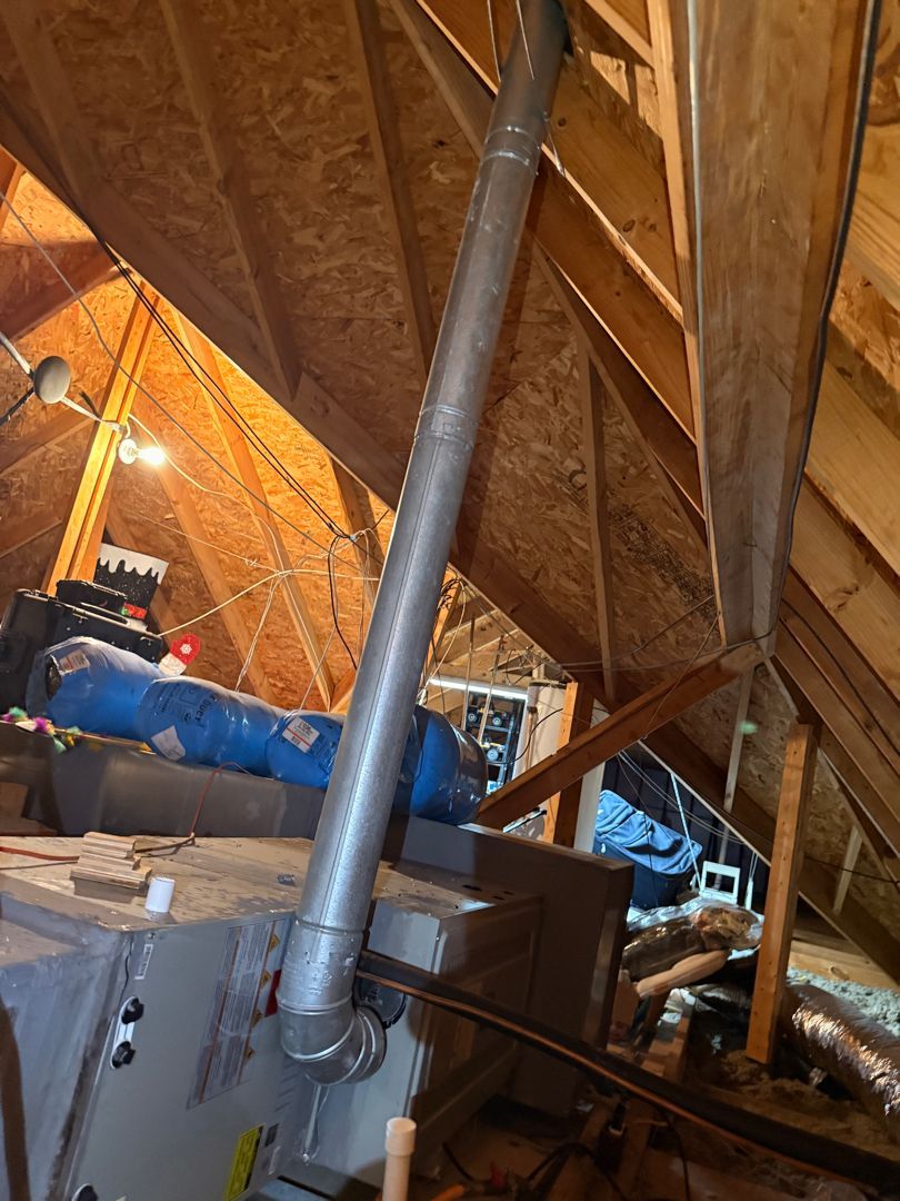 Attic with exposed wooden rafters, metal ductwork, and a blue HVAC unit in a cramped unfinished space