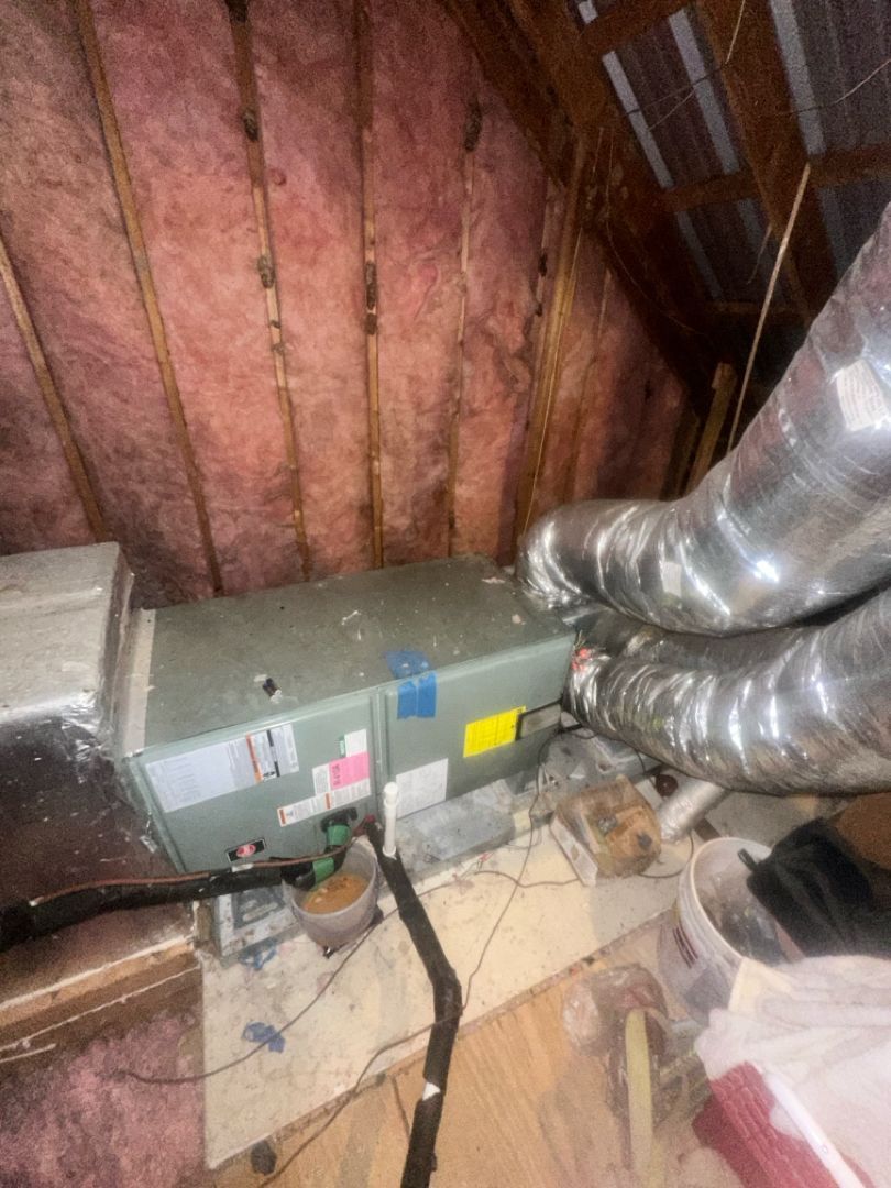 HVAC unit and silver ducts in an unfinished attic with exposed insulation and framing