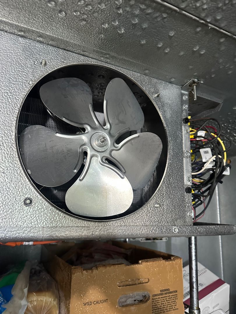 Close-up of a large black fan inside a metal machine housing with visible wiring on the right.