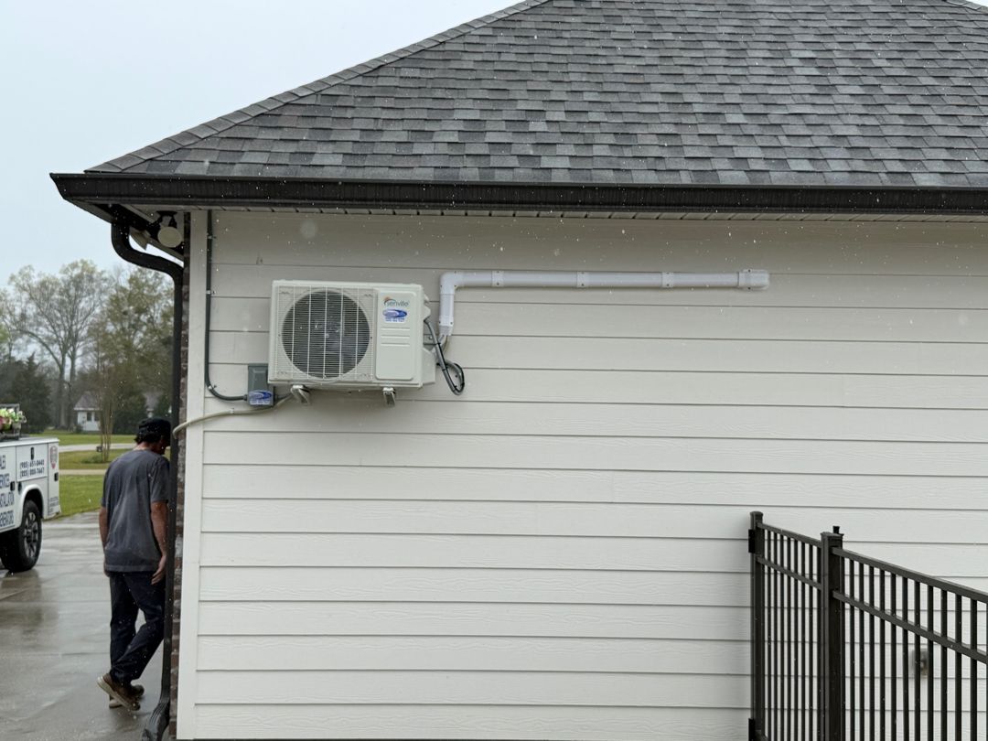 White house exterior with wall-mounted air conditioner and a person walking beside it