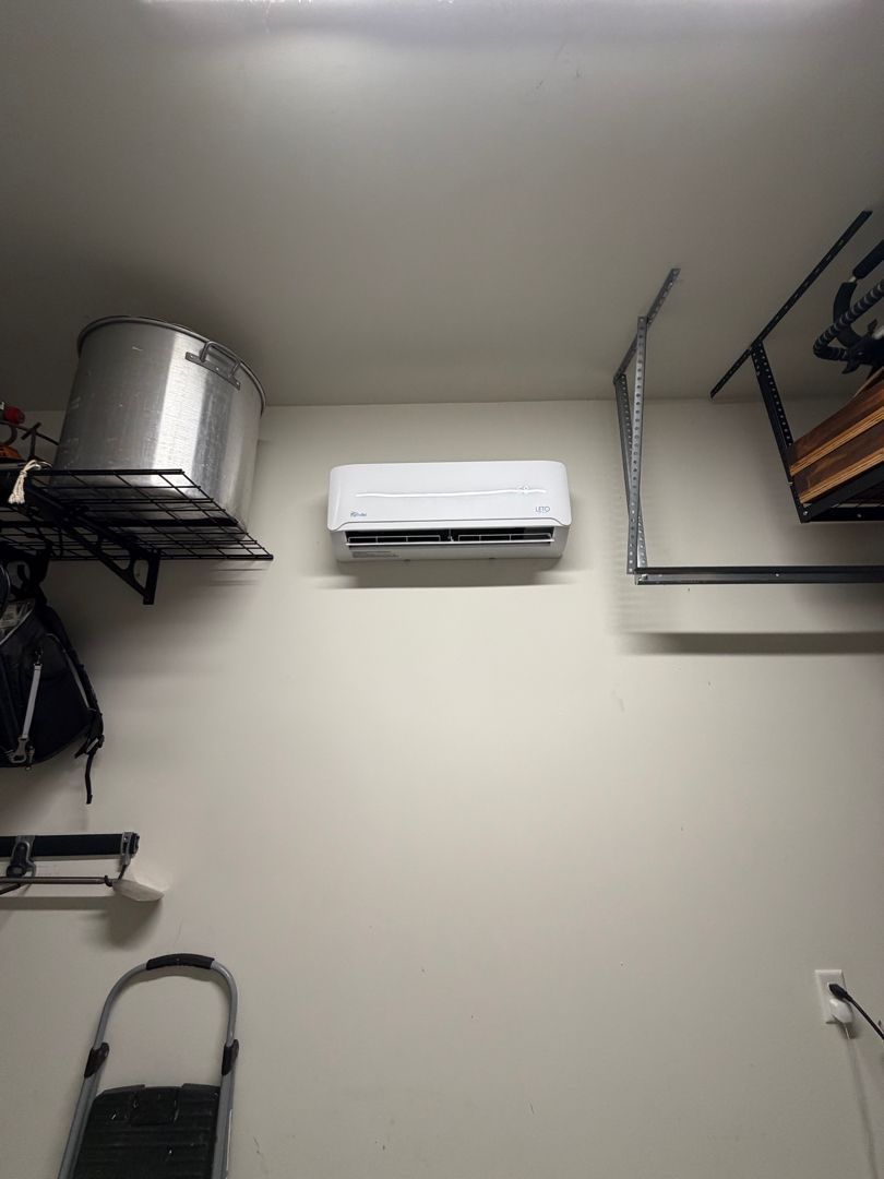 Utility room wall with mounted air conditioner and metal storage shelves on either side.