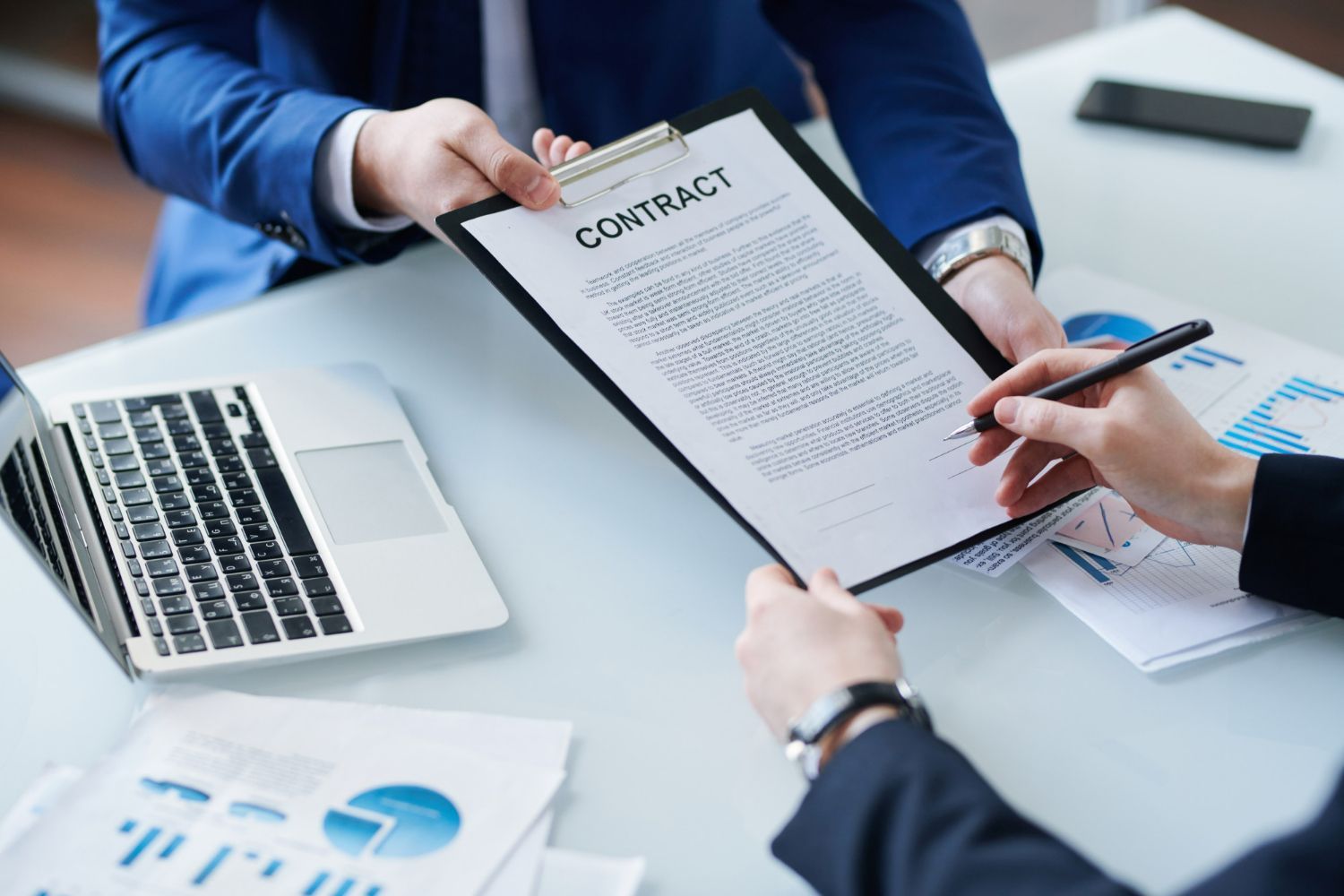 Business professionals in suits exchange a document labeled 