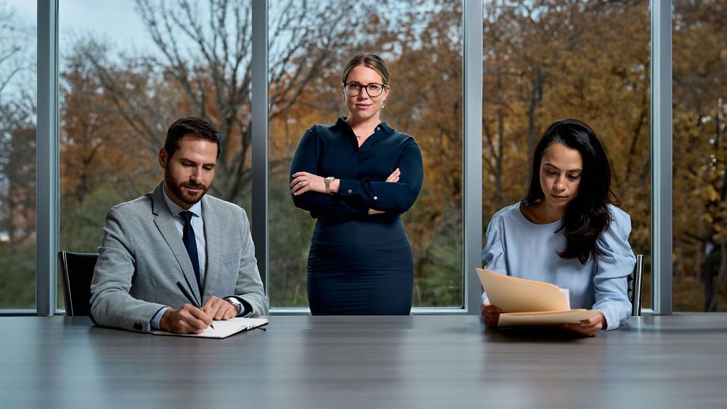 A man and two women are sitting at a table in front of a window.