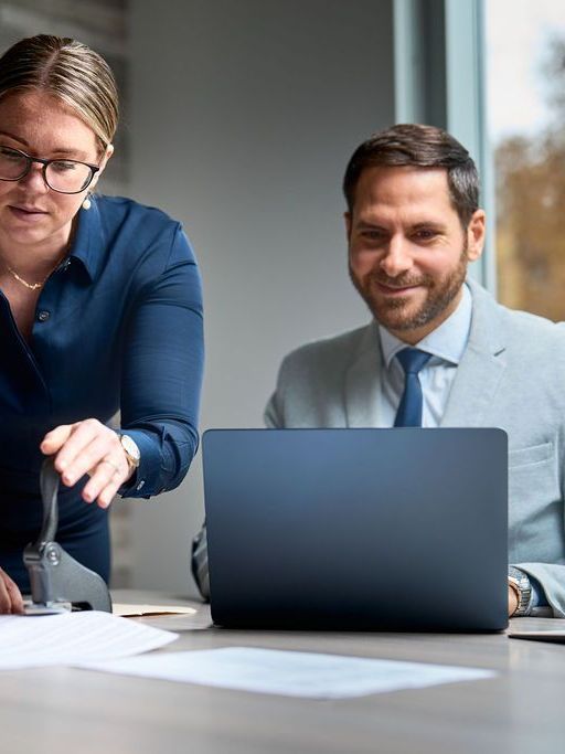 A man and a woman are looking at a laptop computer.