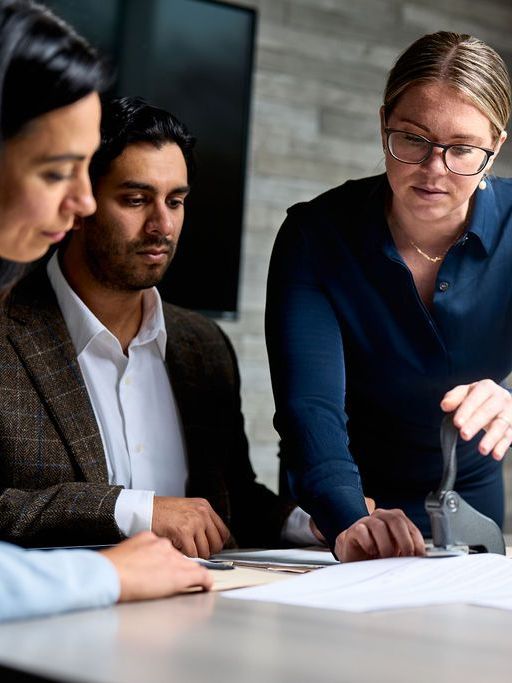 A group of people are sitting around a table looking at a piece of paper.