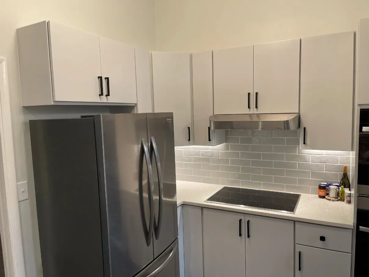 Modern kitchen with stainless steel fridge, white cabinets, and a white-tiled backsplash