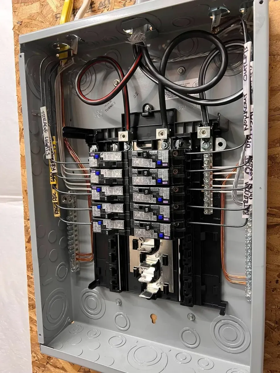 Open electrical breaker panel with rows of circuit breakers and exposed wiring